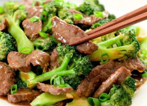close up of beef and broccoli and chopsticks